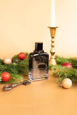 Markasız siyah parfüm şişesi, Noel ağacı, parlak toplar, altın şamdan ve altın arka planda anahtar. Ön görüş, model, şablon. Eau de Tuvalet. Dikey stüdyo fotoğrafı.