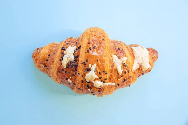 croissant with cheese and sesame seeds on blue background. Closeup, copy space, bakery, top view