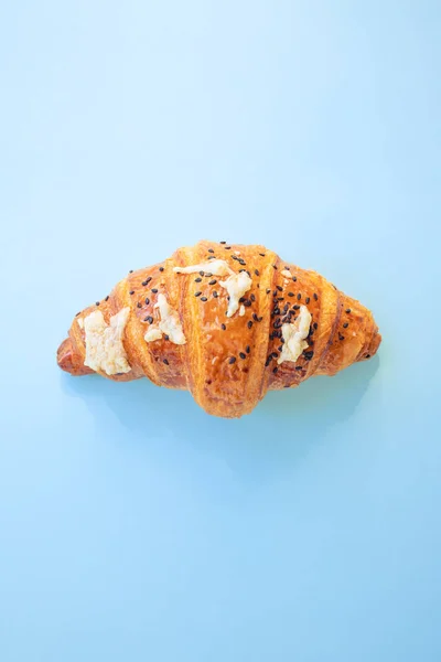 croissant with cheese and sesame seeds on blue background. Closeup, copy space, bakery, top view
