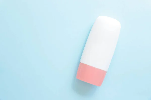 Mockup white cosmetic tube bottle with pink screw cap on blue background. Moisturizing cream, gel, skin care, sunscreen, moisturizer, lotion, Liquid tint. Product branding, front view, copy space