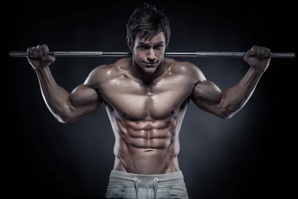 Muscular bodybuilder guy doing exercises with dumbbells over bla — Stock Photo, Image