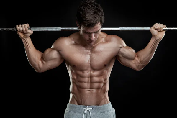 Muscular bodybuilder guy doing exercises with dumbbells over bla — Stock Photo, Image