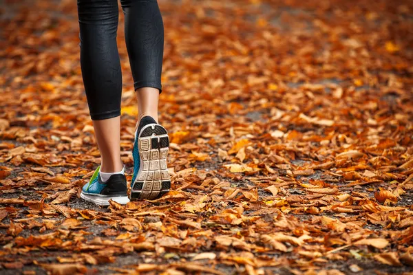 Jovem mulher correndo no início da noite folhas de outono — Fotografia de Stock