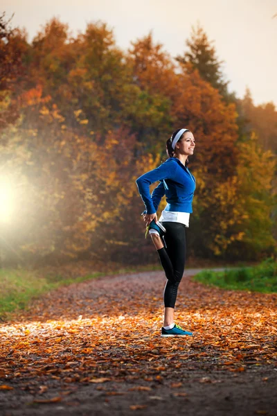 Giovane donna che si allunga prima di correre la sera presto in th — Foto Stock