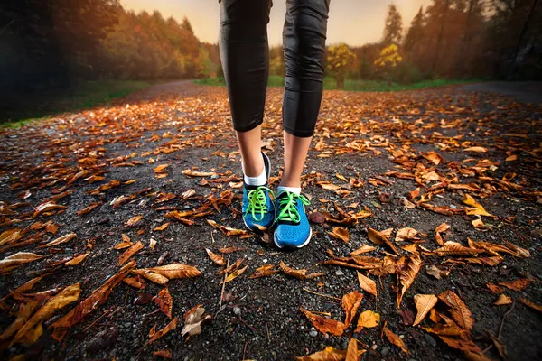 Junge Frau läuft in den frühen Abendstunden Herbstblätter — Stockfoto