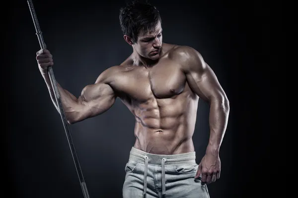 Muscular culturista chico haciendo posando con mancuernas sobre negro — Foto de Stock