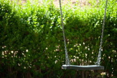 Yeşil arka planda yapayalnız salıncak.