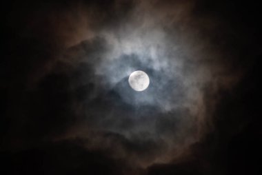 Bulutlu bir gecede yarı gizli dolunay.