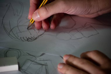 El, kalem ile bir çizim yapıyor, eli ve yarattığı tasarımı yakından görüyor.