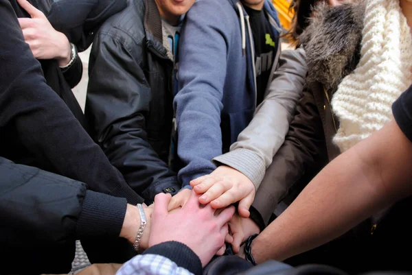 Bir grup genç arkadaştan oluşan bir takım olarak el ele tutuşuyoruz.