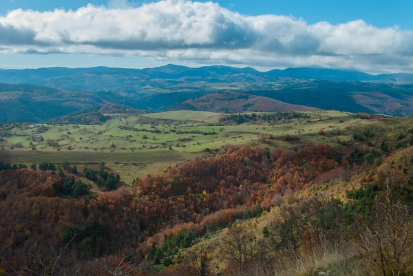 stock image Mountain landscape with forests of green, red, orange and yellow colors that contrast the landscape. Beautiful views of nature with blue and gray skies.