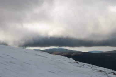 Karla kaplı dağ manzarası ve uzak vadiler ve dağlar.
