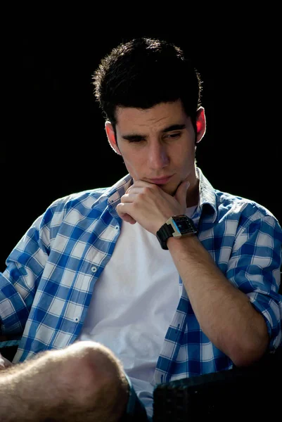 Saati olan zarif bir genç adam, yüzünde düşünceli bir bakışla, elinin üzerine yaslanmış, arkasında koyu bir arka planla.