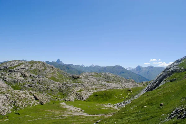Dağlık yeşil dağ sıraları, açık mavi gökyüzü ve birkaç bulutla kaplı..
