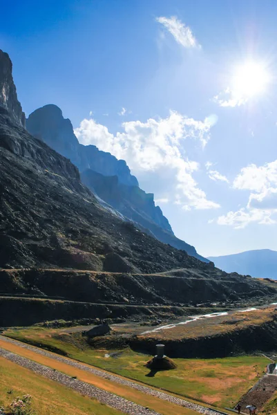 Güneşin doğuşu ya da batışı yüksek dağlarda, yeşil bir vadide ve bulutlu açık bir gökyüzünde