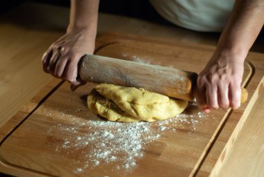 Baker 'ın elleri tahtanın üzerinde un hamuru üzerinde çalışıyor.
