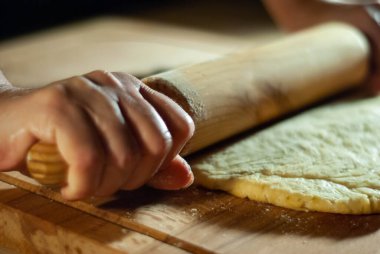 Baker 'ın elleri tahtanın üzerinde un hamuru üzerinde çalışıyor.