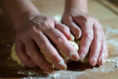 Baker 'ın elleri tahtanın üzerinde un hamuru üzerinde çalışıyor.