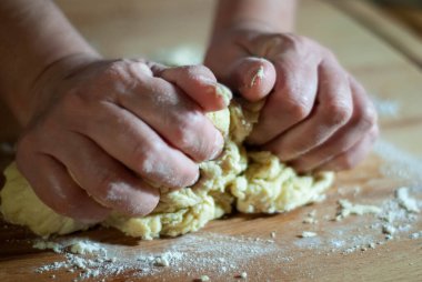 Baker 'ın elleri tahtanın üzerinde un hamuru üzerinde çalışıyor.