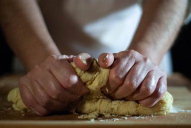 Baker 'ın elleri tahtanın üzerinde un hamuru üzerinde çalışıyor.