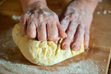 Baker 'ın elleri tahtanın üzerinde un hamuru üzerinde çalışıyor.
