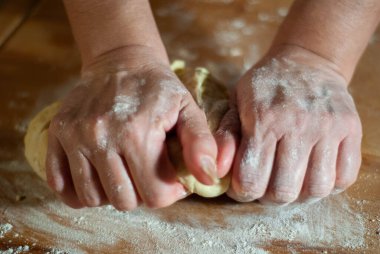 Baker 'ın elleri tahtanın üzerinde un hamuru üzerinde çalışıyor.