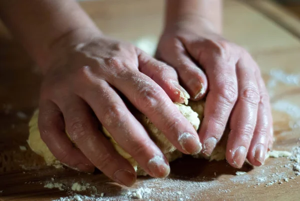 Baker 'ın elleri tahtanın üzerinde un hamuru üzerinde çalışıyor.