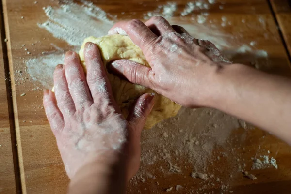 Baker 'ın elleri tahtanın üzerinde un hamuru üzerinde çalışıyor.