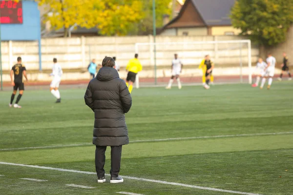 Futbol koçu maçı arkadan izliyor.