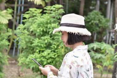 Cep telefonu kullanan güzel bir kadının portresi açık hava parkında internette sörf yapıyor..