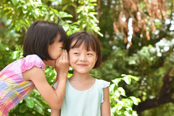 公園の屋外で耳にささやく2人の妹の女の子の閉じる 人々の概念 — ストック写真
