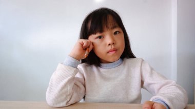 Beyaz gömlekli, yarım saçlı bir kızın resmi. Duvarın arka planında oturmayı düşünüyorum..