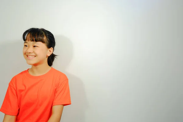 Boş Zamanlarında Gülümseyen Asyalı Kız Beyaz Arka Planda Turuncu Gömlek — Stok fotoğraf