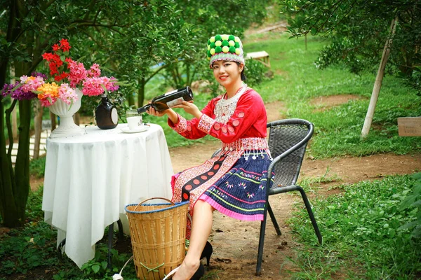 部落女农民在户外橘园里喝果汁的背景 — 图库照片