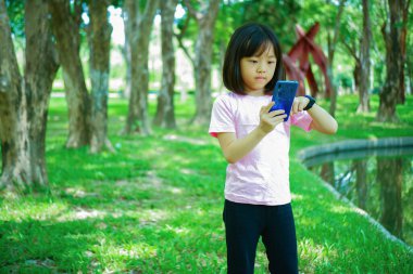 Asyalı kızın arka planı telefonda gülen yüzünü gösteriyor.