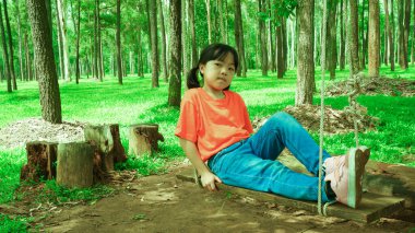 Asyalı kızlar bahçedeki çocuk parkında eğleniyor..