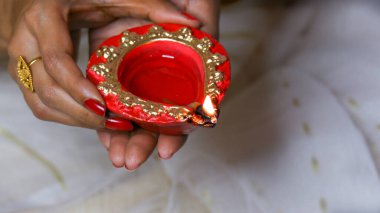 Kadın, Diwali olayında kırmızı diya lambasını ya da ışığı iki eliyle tutuyor ve alevi var..