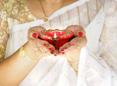 Kadın, Diwali olayında kırmızı diya lambasını ya da ışığı iki eliyle tutuyor ve alevi var..