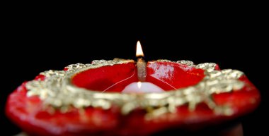 Kırmızı renkli diya 'nın yakın plan görüntüsü ya da arka plandaki koyu arkaplan ateşine odaklanmış ışık..