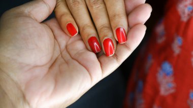 Tırnakları kırmızı ojeli bir kızın eli oğlanın elinde..