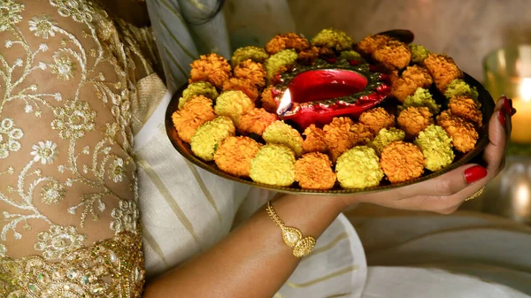 Kadın, Diwali olayında kırmızı diya lambasını ya da hafif thali 'yi iki eliyle tutuyor ve alevi var..