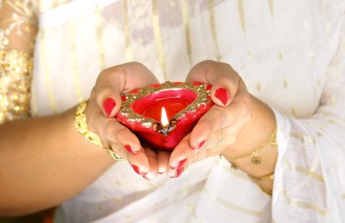 Kadın, Diwali olayında kırmızı diya lambasını ya da ışığı iki eliyle tutuyor ve alevi var..