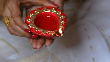 Kadın, Diwali olayında kırmızı diya lambasını ya da ışığı iki eliyle tutuyor ve alevi var..