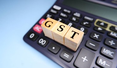 Tahta boncuklar ya da bloklar üzerindeki harflerle GST ya da Mal ve Hizmetler Vergisi ve hesap makinesiyle GST hesaplanıyor.