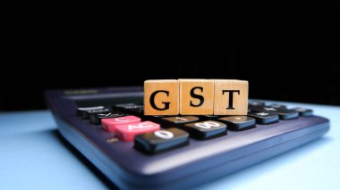 Tahta boncuklar ya da bloklar üzerindeki harflerle GST ya da Mal ve Hizmetler Vergisi ve hesap makinesiyle GST hesaplanıyor.