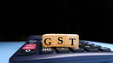 Tahta boncuklar ya da bloklar üzerindeki harflerle GST ya da Mal ve Hizmetler Vergisi ve hesap makinesiyle GST hesaplanıyor.