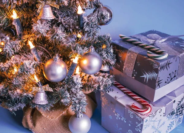 Yapay Noel ağacı, toplar, çanlar, parlak çelenkler ve kar ile süslenmiş gümüş şeker kamışlarıyla süslenmiş ve arkaplanda 2022 yılının yeni rengi olan Çok Peri 'nin kurdeleleriyle süslenmiş. Noel ve Yeni Yıl geçmişi. Kış tatili kavramı