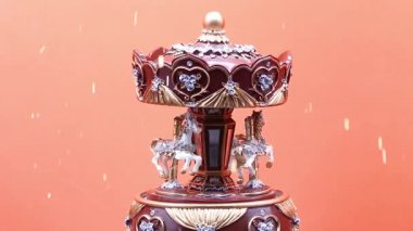 Oyuncak atlıkarınca müzik kutusu turuncu arka planda ve beyaz atlar ağır çekimde,