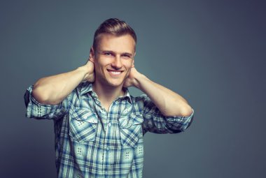 gri arka planı ayakta gülümseyen genç adam bl giyinmiş