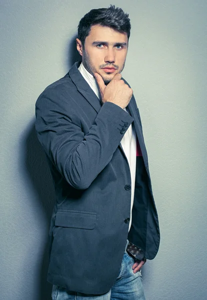 Smiling young man standing against gray background dressed in bl